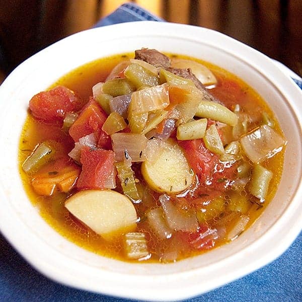 A serving of homemade vegetable beef soup in a white bowl.