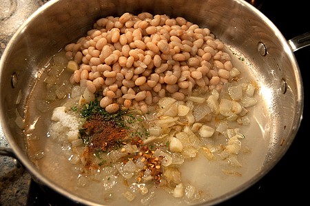 Beans and other ingredients added to a skillet.