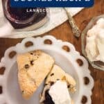 Two Irish currant scones on a white plate with jam and whipped cream, recipe text above.