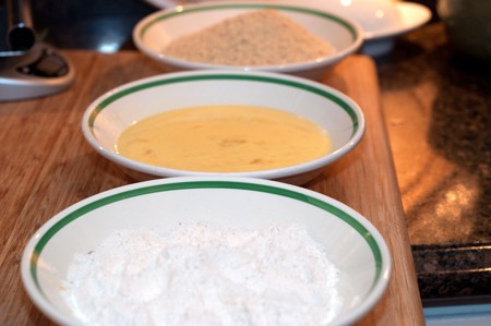 Breading station consisting of three bowls; one each of flour, egg wash, and panko bread crumbs