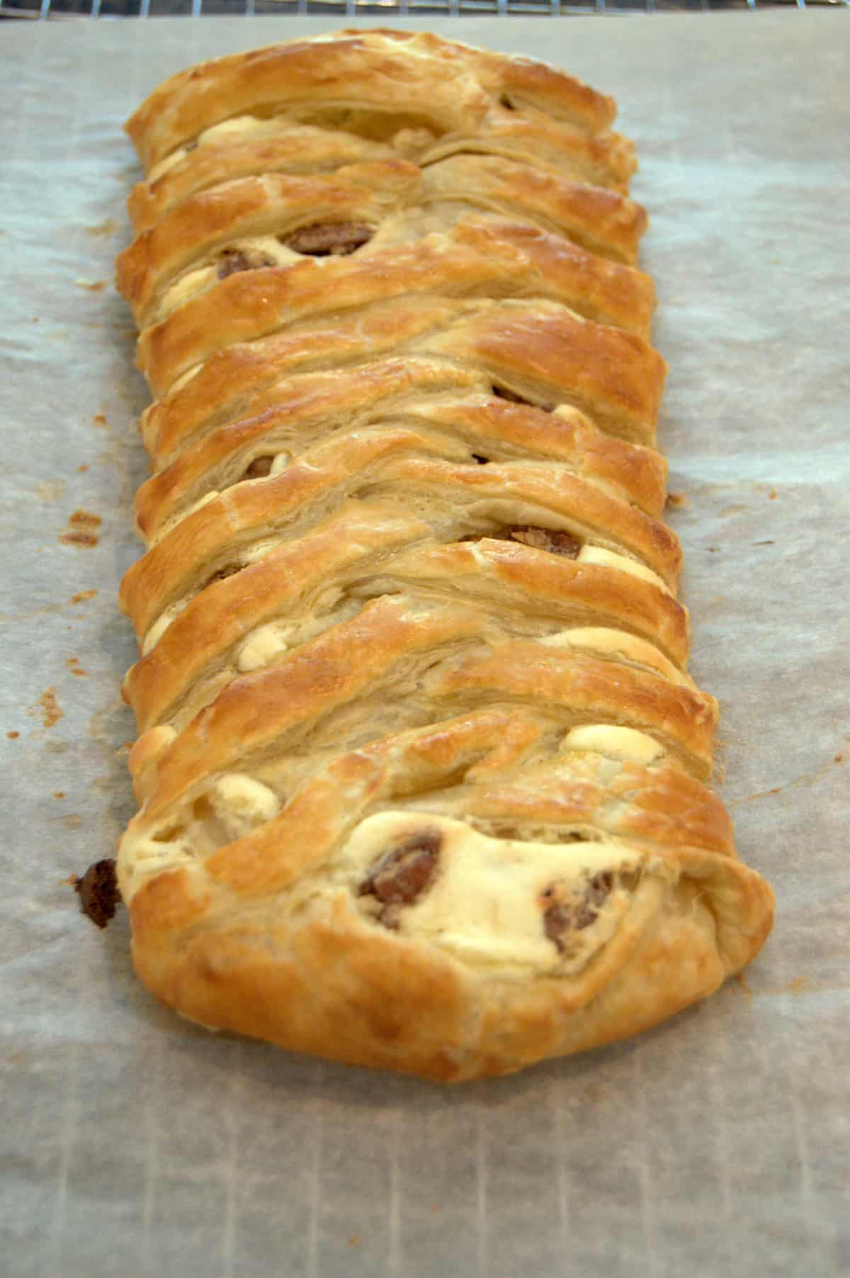 Finished cheese braid cooling on parchment paper.