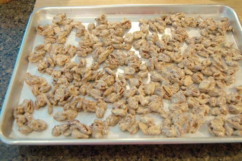 Candied pecans cooling on a baking sheet.
