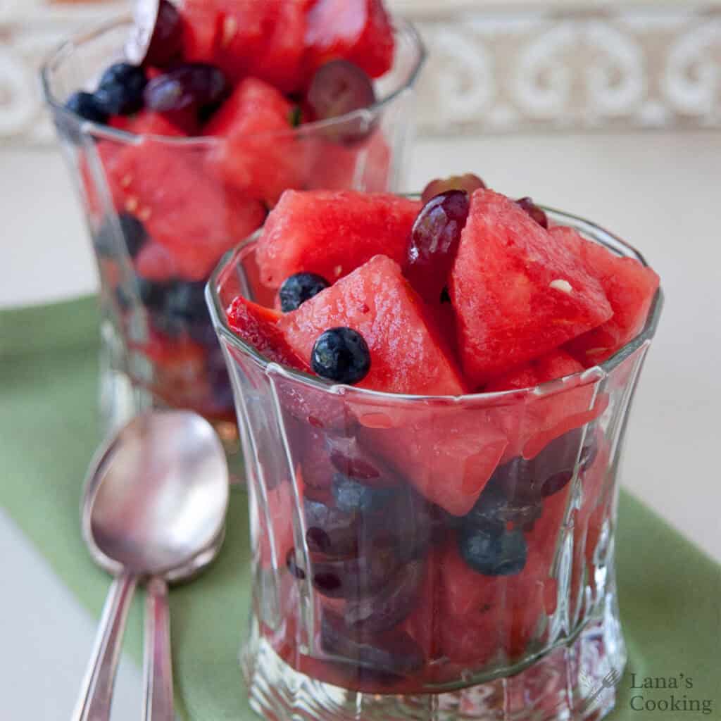 Two glasses filled with a refreshing watermelon salad sit alongside two spoons, ready to enjoy.