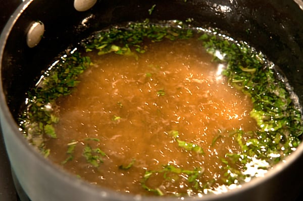 Water, sugar, mint, and ginger cooking in a saucepan.