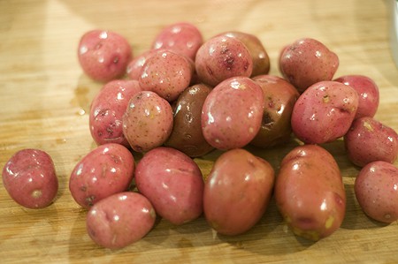 Washed red skinned potatoes on a board.