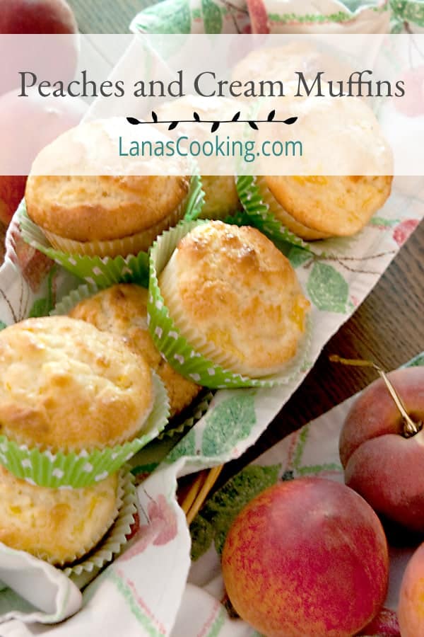 A basket full of peaches and cream muffins with fresh peaches in the foreground.