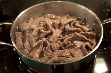 Steak strips browning in a skillet.