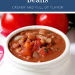A white bowl of Cowgirl Beans featuring visible tomatoes, onions, and beans.