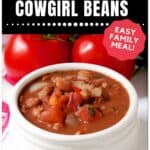 A white bowl filled with cowgirl beans, featuring tomatoes, onions, and beans in a red sauce. Two whole tomatoes are in the background. Text on the image promotes the recipe as hearty, delicious, and an easy family meal.