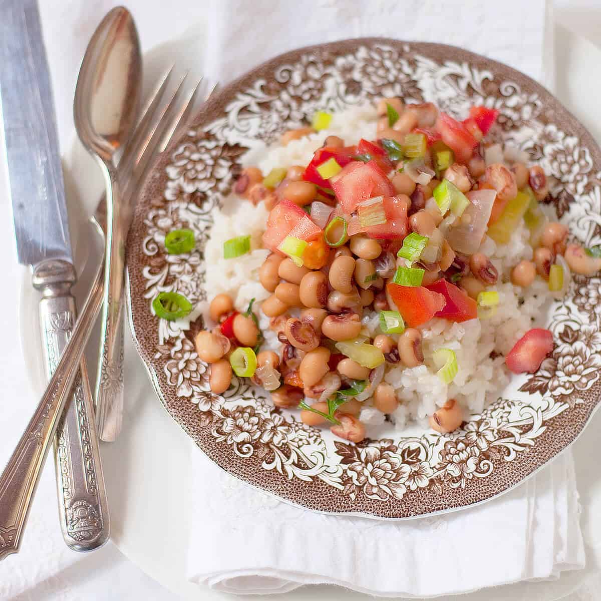 A serving of Hoppin' John on a vintage plate with antique flatware.