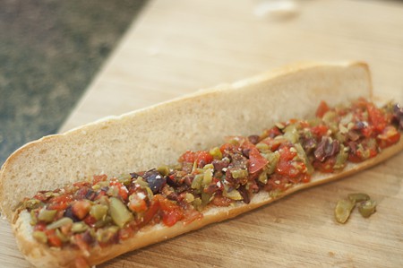 Mediterranean Tartine filling Cut baguette spread with vegetable filling.