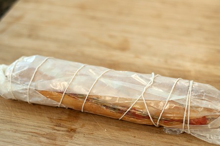 Wrapped Mediterranean Tartine Filled baguette wrapped in waxed paper and tied with string.