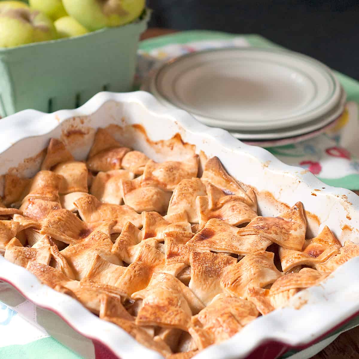 Apple Patchwork Cobbler in a baking dish with serving plates in the background.