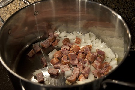 Sausage, onions, and garlic cooking in a large pot.