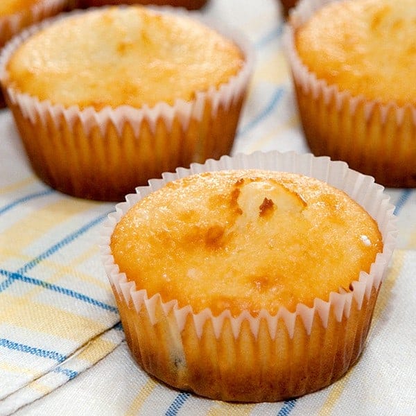 Golden brown lemon and cherry muffins on a decorative napkin.