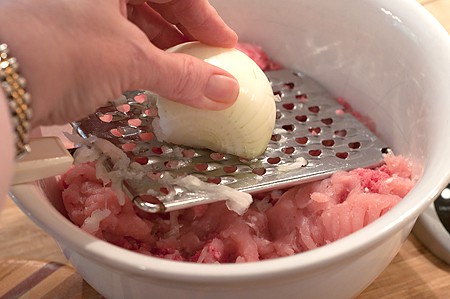 Grating onion into bowl.