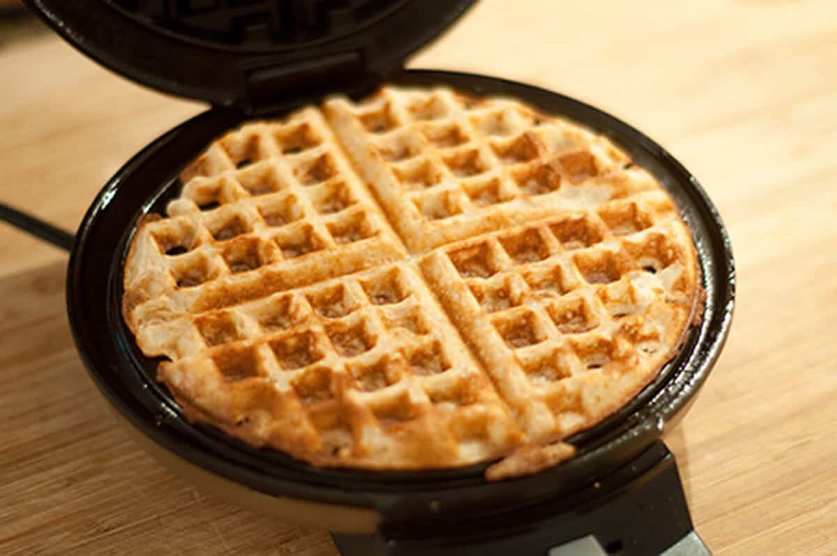 Cooked waffle inside a waffle iron.