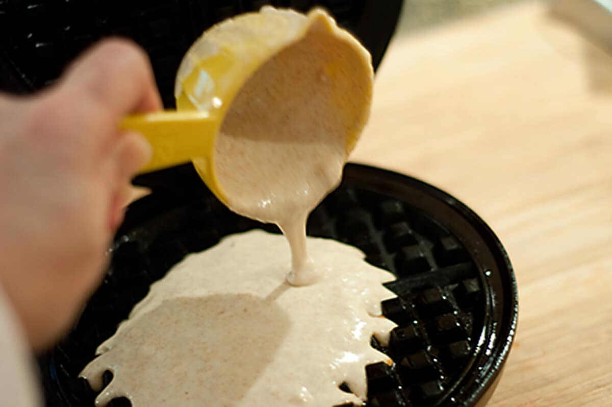 Pouring batter into a waffle iron.
