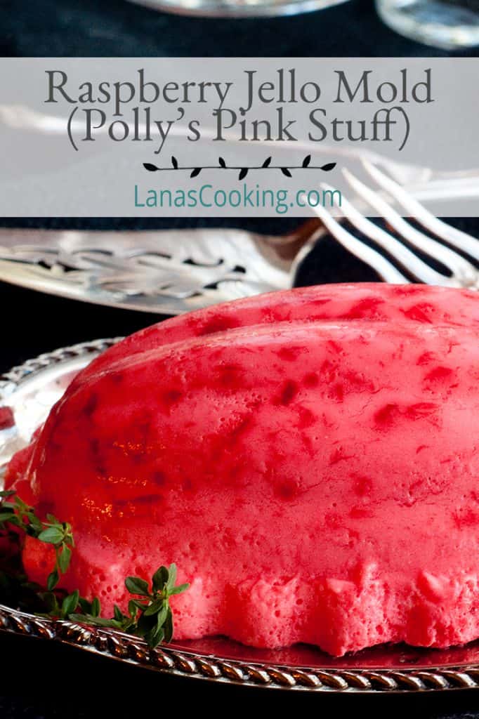 Raspberry jello mold on a silver serving tray with vintage serving pieces in the background. Text overlay for pinning.
