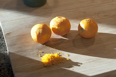 Three clementines and their zest on a board.