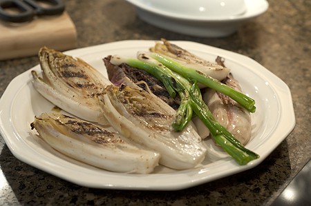 Grilled endive and green onions on a white plate.