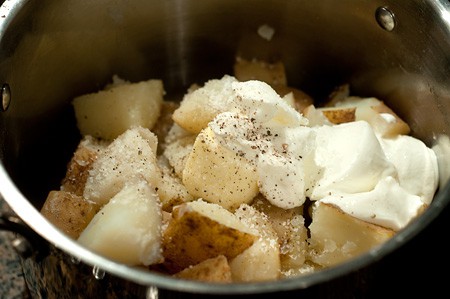 Cooked potatoes in a pot with butter, sour cream, salt and pepper.