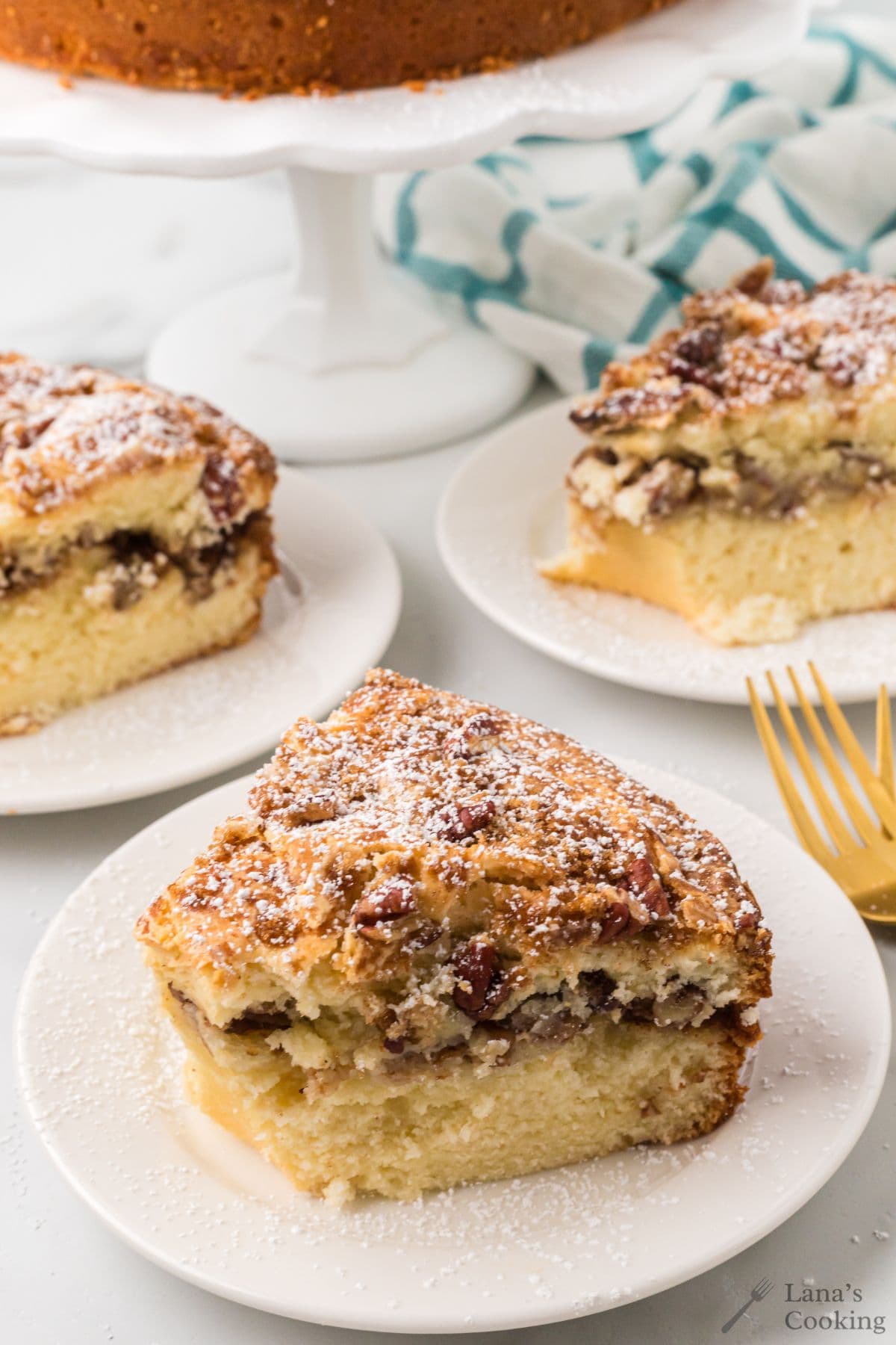 Slices of sour cream coffee cake on a white plate with a gold fork.