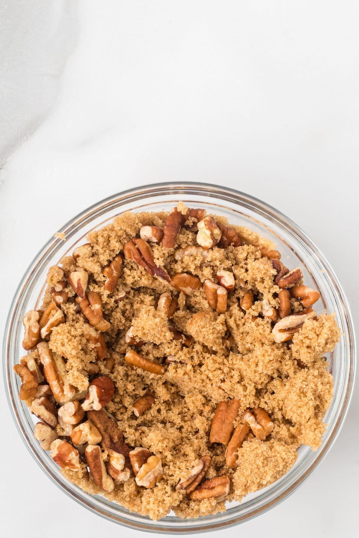 Pecans, brown sugar, and cinnamon in a glass bowl.