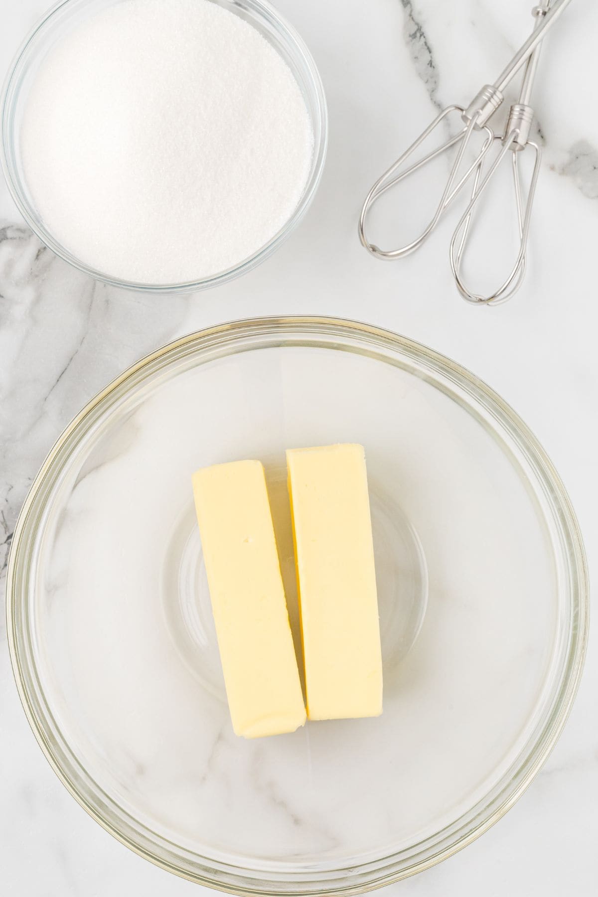 Butter in a glass bowl on a marble surface.