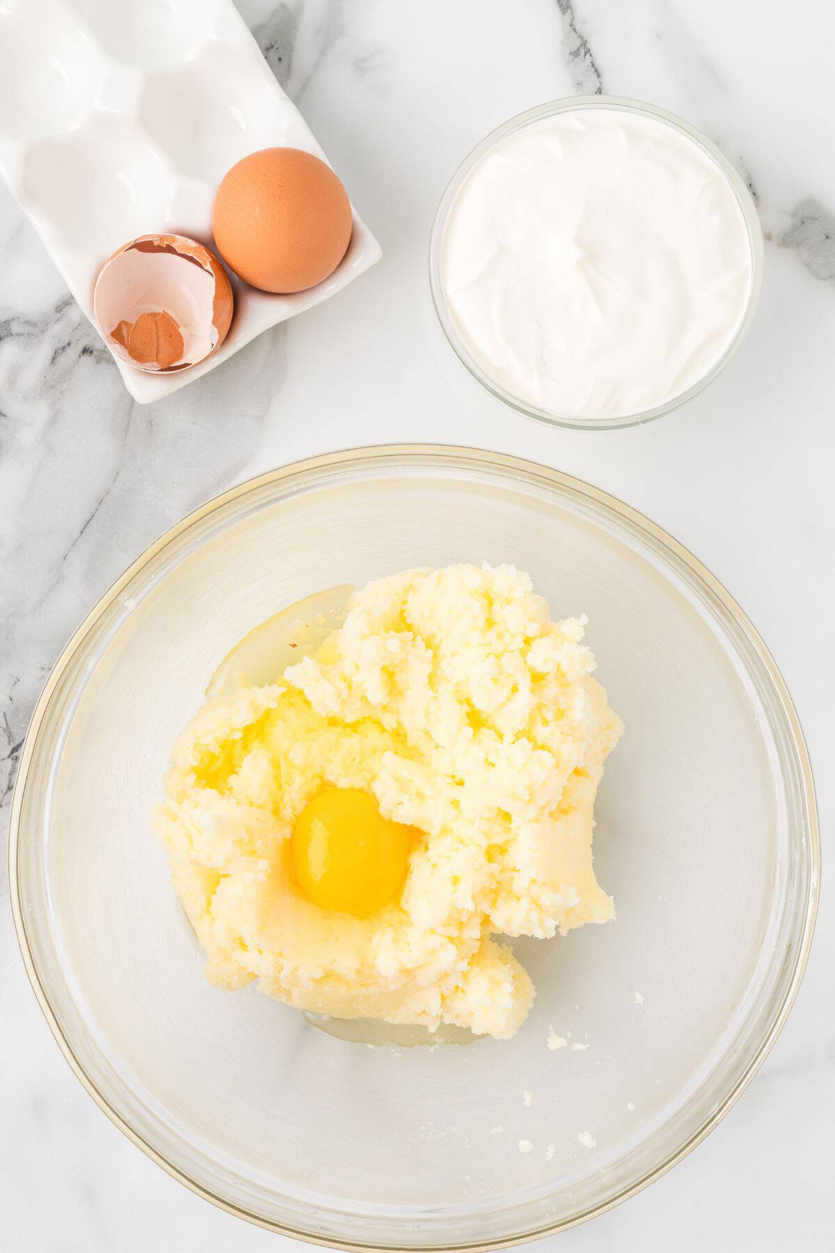 Creamed butter with an egg cracked on top before being mixed together.