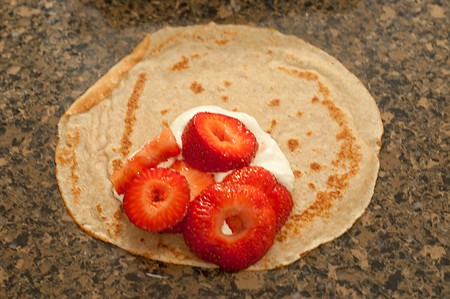 Filling crepes with strawberries and whipped cream.