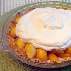 Heavenly Peach Pie with a sour cream filling in an almond and coconut pie shell. The perfect way to highlight delicious fresh peaches in season. https://www.lanascooking.com/heavenly-peach-pie/