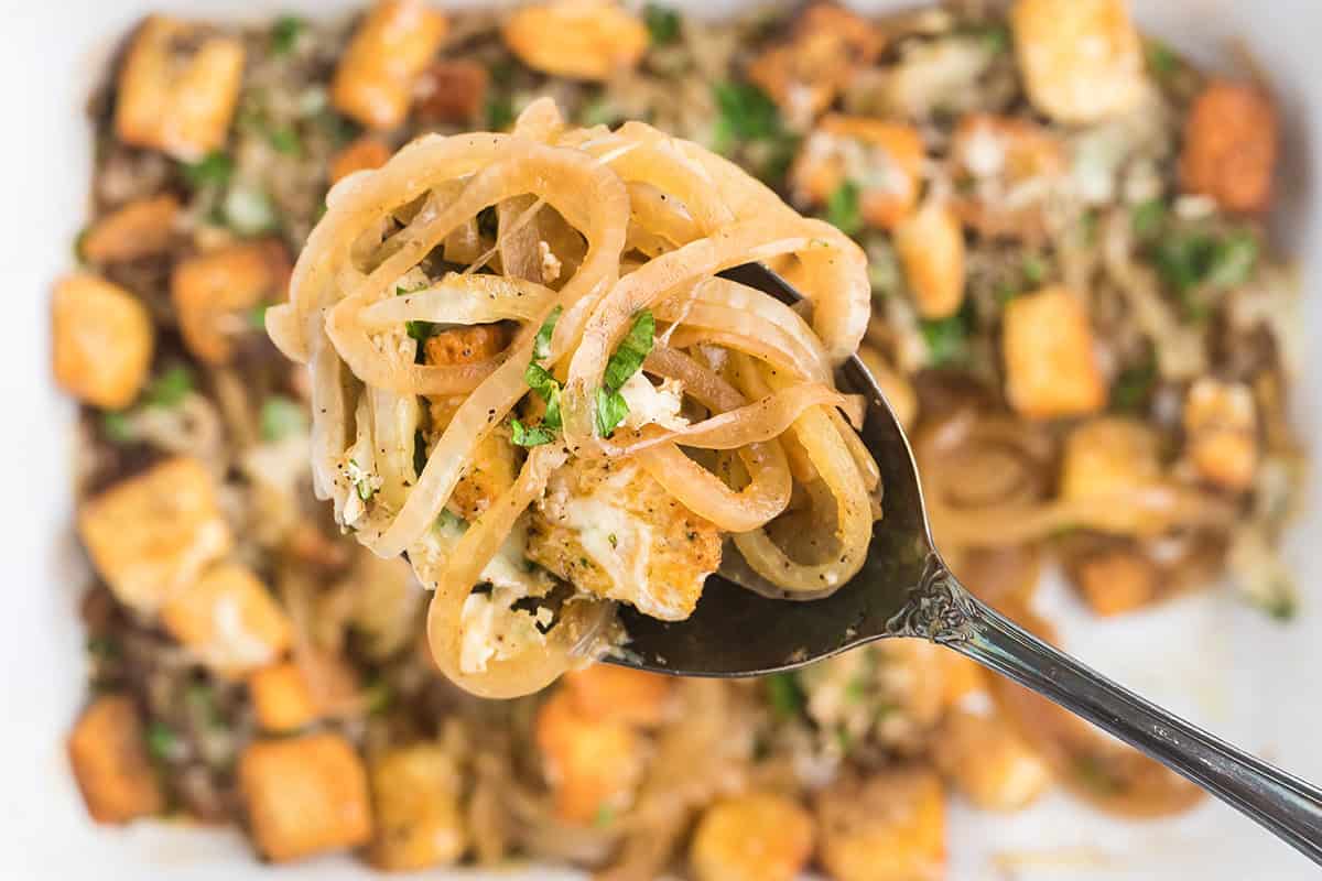 A spoon holding a scoop of finished onion gratin.