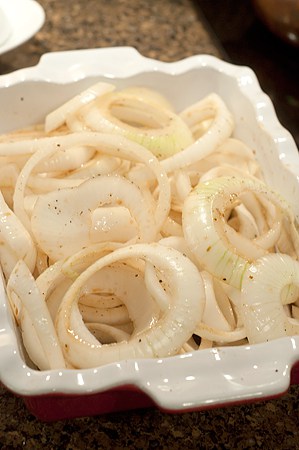 Sliced onions in a baking dish.