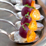 Pickled baby beets with herbed goat cheese presented in individual silver spoons.