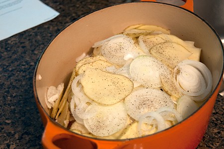 Adding potatoes and onions to the pot.