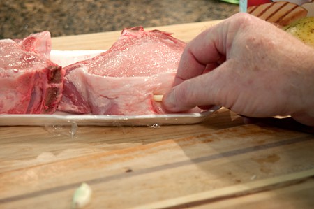 Inserting garlic slivers into pork chops.