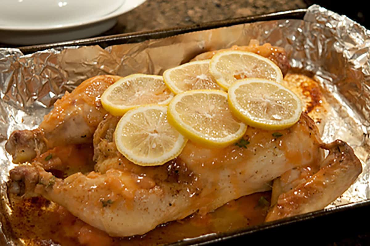 Applying sauce to chicken in a baking pan.