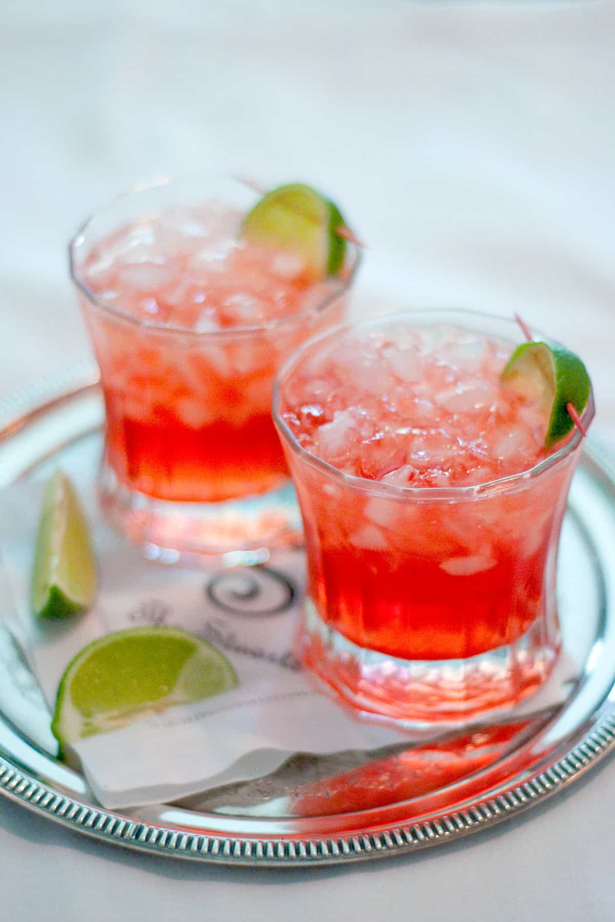 Two Scarlett O'Hara cocktails on a silver tray with lime garnish.