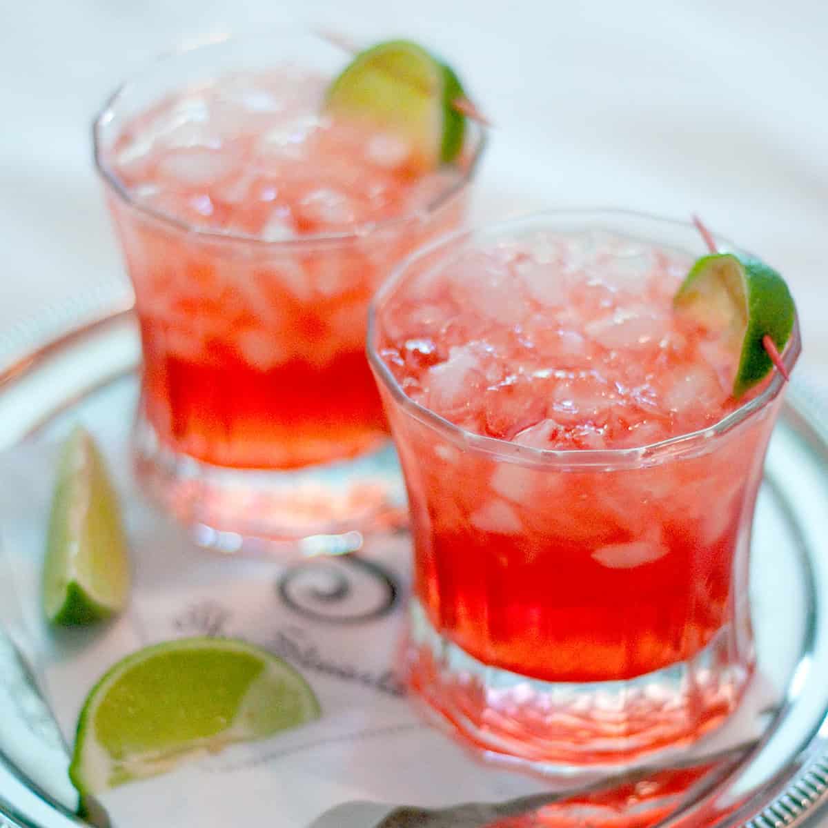 Two Scarlett O'Hara cocktails on a silver tray with lime garnish.