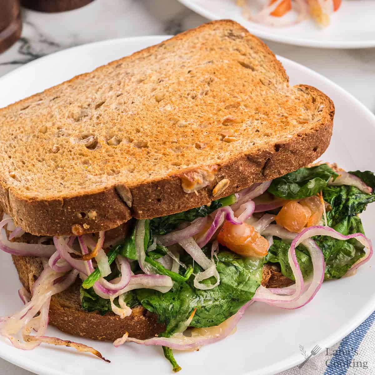 Finished sandwich on a white serving plate.