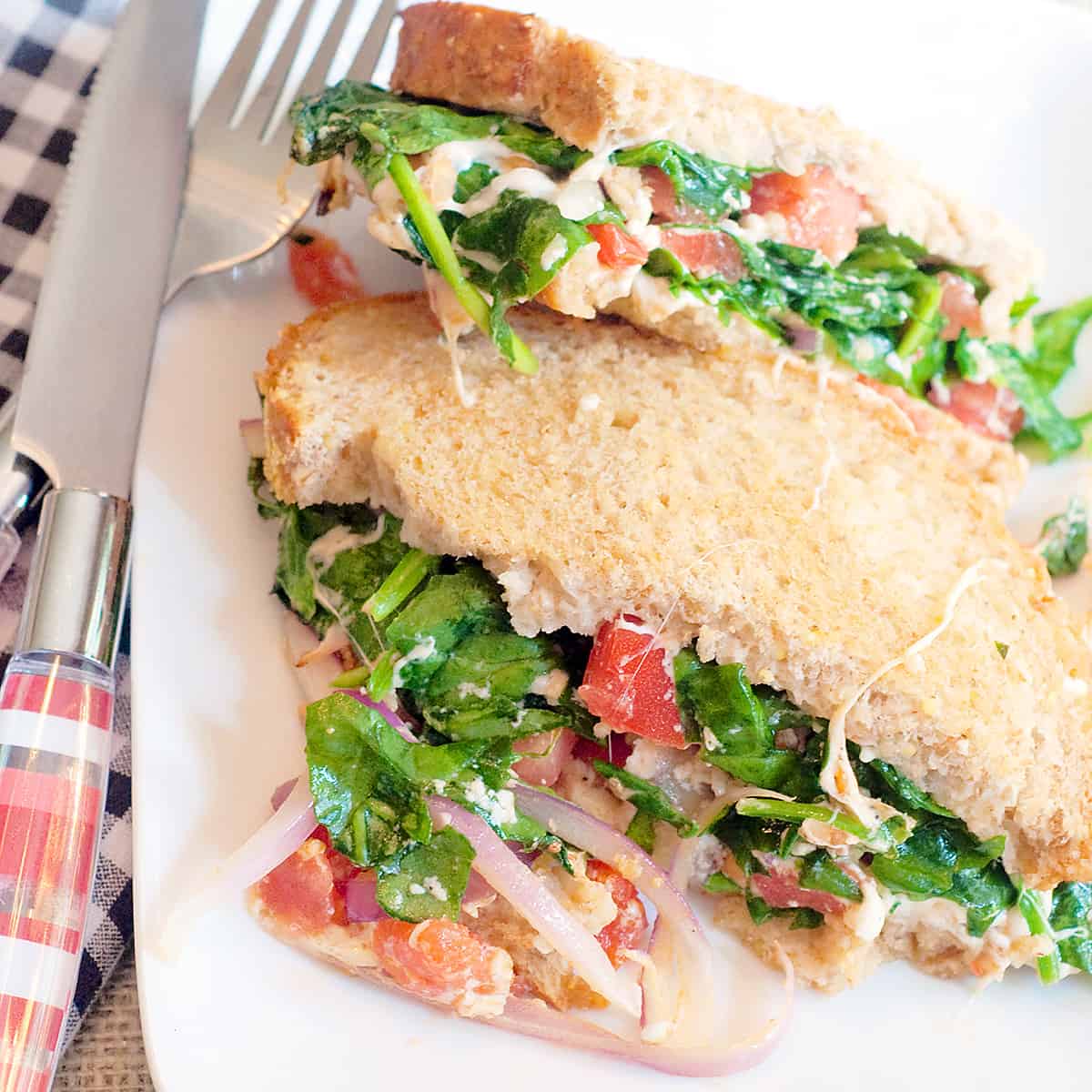 Grilled Cheese Florentine on a white serving plate with a napkin, knife, and fork alongside.