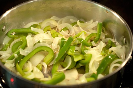Peppers and onions cooking in a skillet.