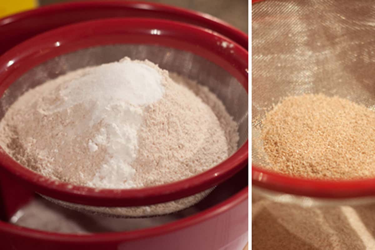 Flour and baking soda in a red mesh sieve, with bran remaining in the sieve after sifting.