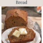 A slice of carrot pecan bread on a plate, topped with butter and syrup, with a loaf in the background.