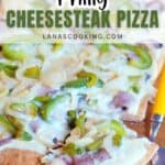 Rectangular Philly cheesesteak pizza topped with melted cheese, green bell peppers, onions, and steak pieces on a wooden board with a pizza cutter.