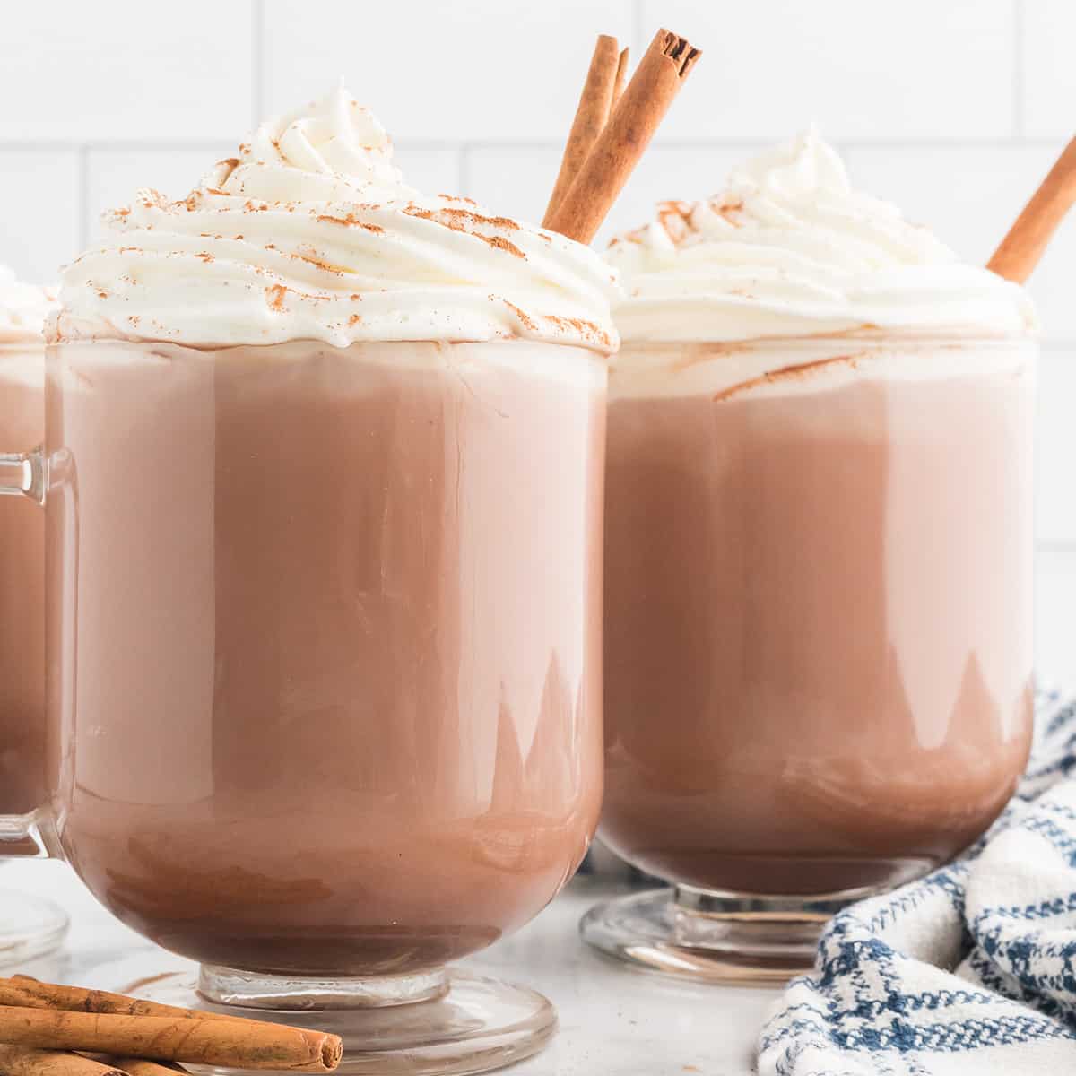Three cups of hot chocolate with whipped cream and cinnamon on top.