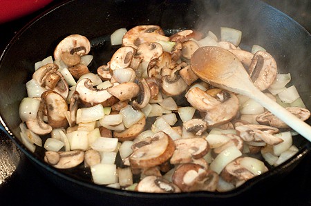 Onions and mushrooms cooking in a cast iron skillet
