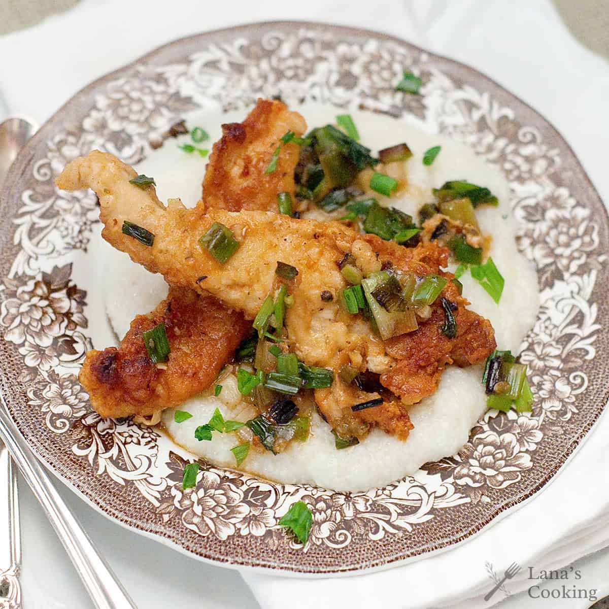 A serving of chicken with grits on a decorative plate.