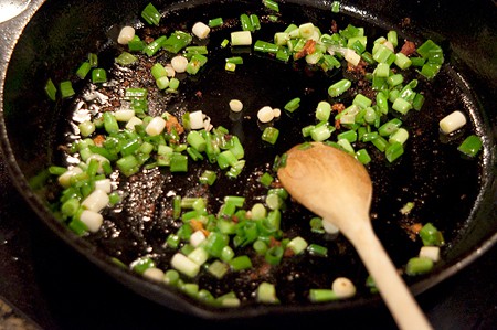 Cooking green onions in a skillet.